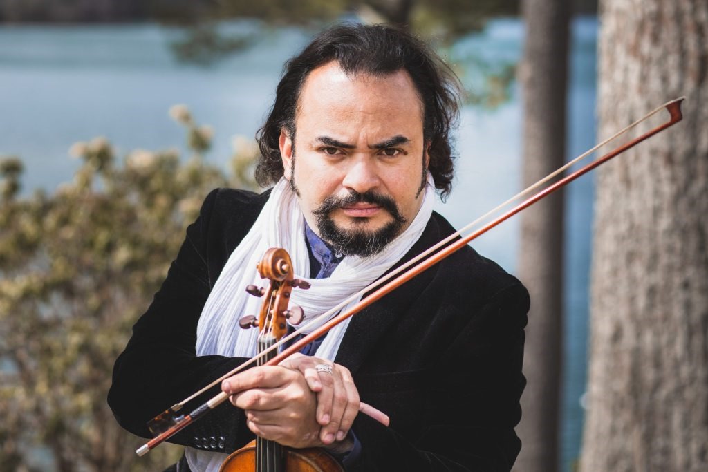 Alexis Cárdenas, violinista venezolano, posa con su violín en un entorno natural.