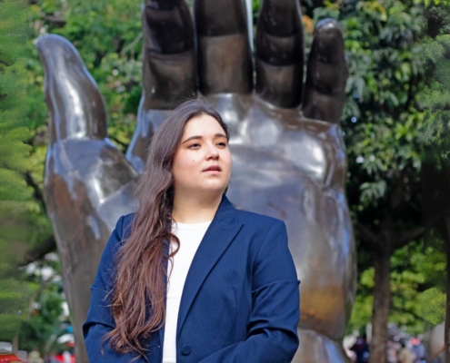 Ana María Patiño-Osorio, nueva directora titular de la Orquesta Filarmónica de Medellín, posando junto al río Medellín con batuta en mano.