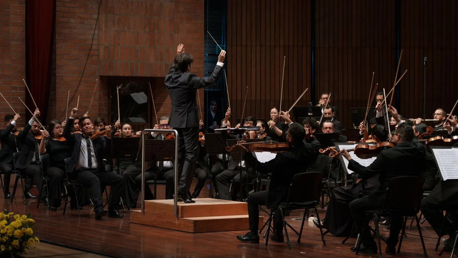 Orquesta Filarmónica de Medellín al final de un concierto sinfónico, con el director y los músicos levantando sus arcos en señal de agradecimiento