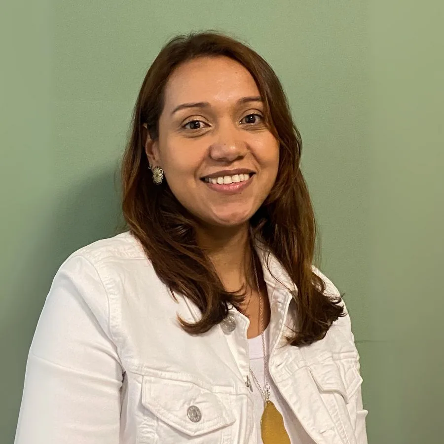 Elizabeth Castañeda, líder de desarrollo organizacional y social en la orquesta filarmónica, sonriendo frente a un fondo verde.