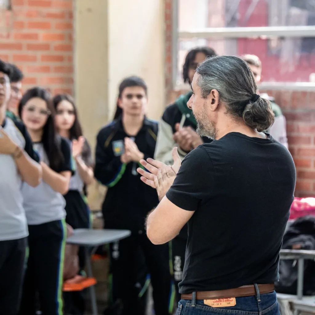Docente liderando actividad rítmica con estudiantes de secundaria durante un taller educativo de la Orquesta Filarmónica de Medellín