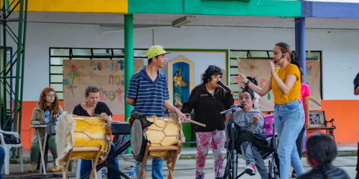 Personas con discapacidad y talleristas participando en un programa social de la Orquesta Filarmónica de Medellín, tocando instrumentos y cantando en un espacio comunitario