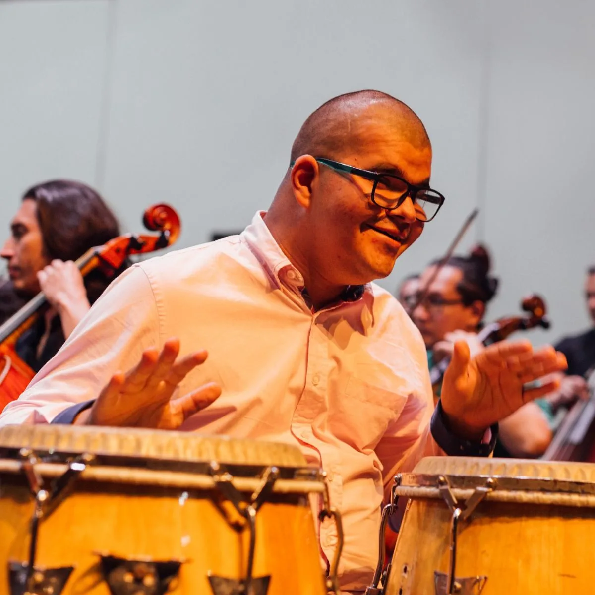Hombre con discapacidad cognitiva toca congas durante presentación musical inclusiva junto a una orquesta.