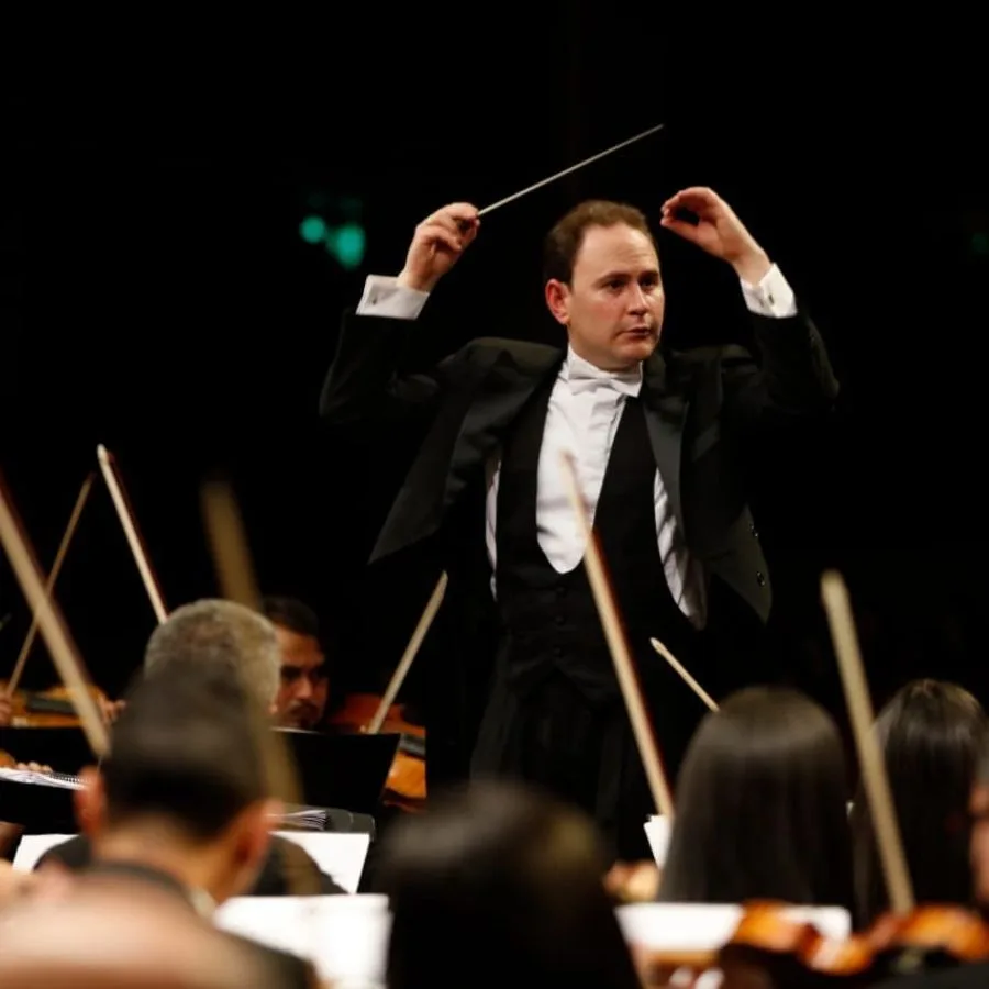 Christian Vásquez dirigiendo la orquesta durante un concierto con batuta en mano