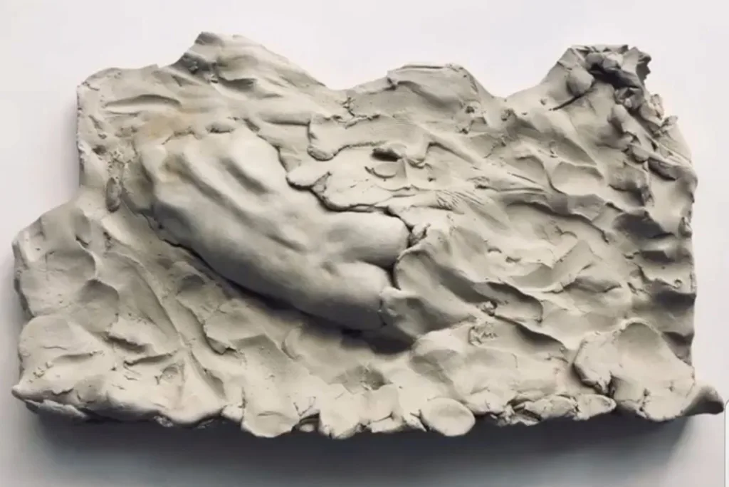 Escultura en arcilla de Camilo Martínez que representa una mano emergiendo de una superficie rugosa y orgánica.