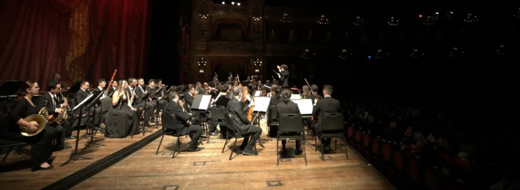 La Orquesta Filarmónica de Medellín interpretando un concierto en un teatro histórico lleno de público, durante su primera gira internacional.