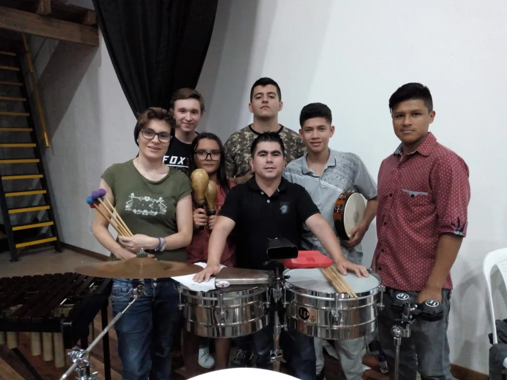 Jhon Freddy, con camisa negra, posa con un grupo de jóvenes percusionistas en una sala de ensayo de la Escuela de Música de Ciudad Bolívar.