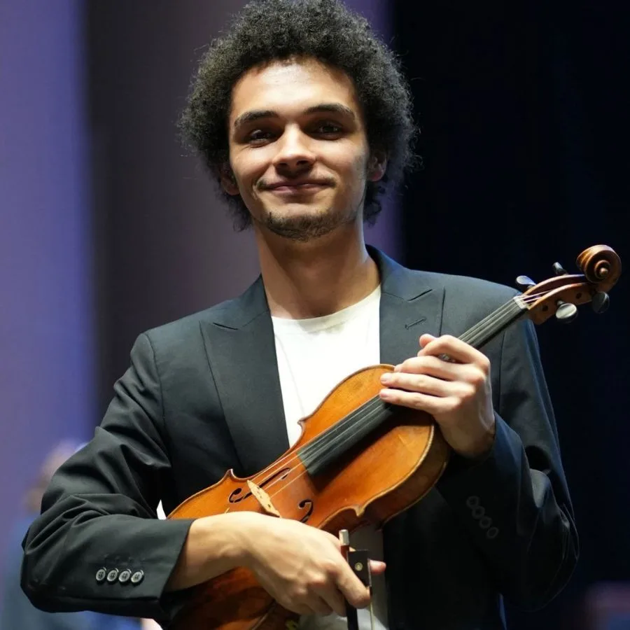 Juan Andrés sosteniendo su violín con una expresión de orgullo en el escenario