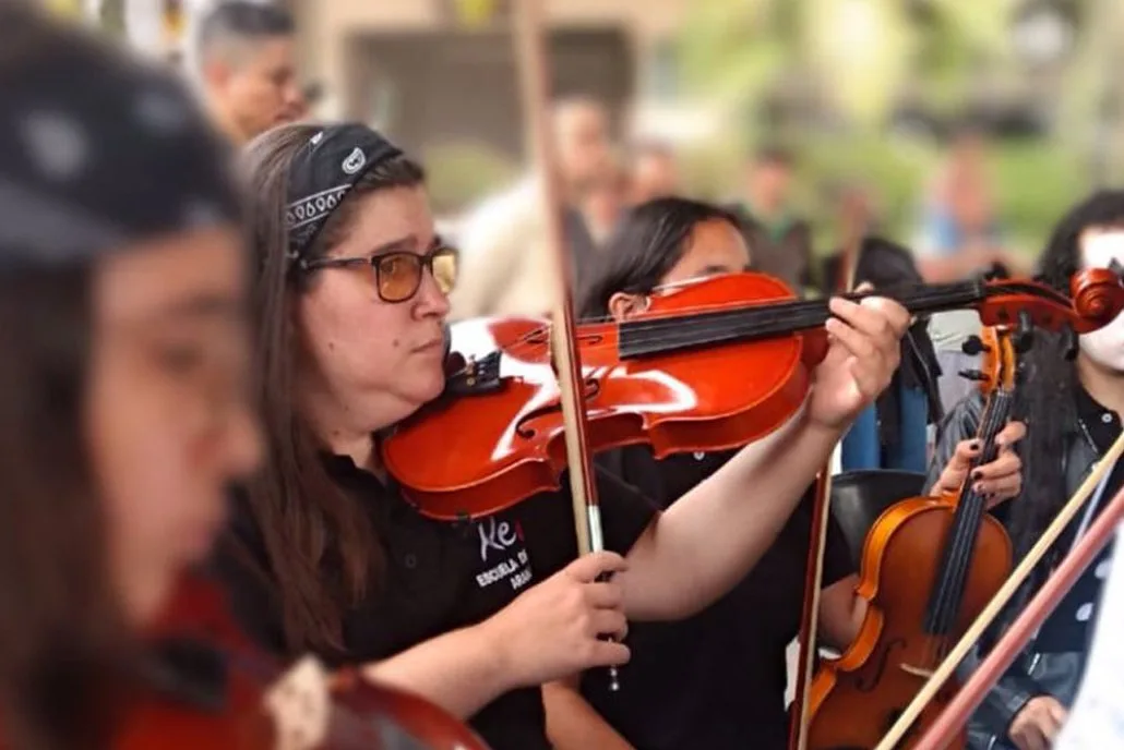 Kelly interpretando la viola en un concierto colectivo al aire libre