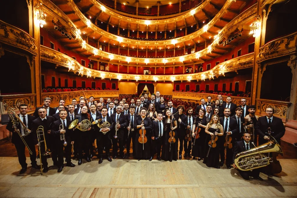 La Orquesta Filarmónica de Medellín posando en el escenario del Teatro Metropolitano, con todos sus músicos reunidos frente al público.