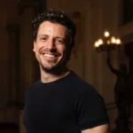 Paolo Bortolameolli sonriendo en un teatro iluminado, vestido con camiseta negra