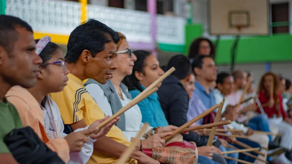 Grupo diverso de personas participando en un taller de percusión con palos de madera, como parte del programa Soy Músico de la Orquesta Filarmónica de Medellín.