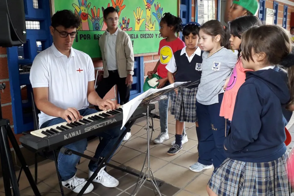Tomás tocando el teclado electrónico mientras un grupo de niños lo observa con atención en un entorno escolar