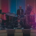 Grupo de personas en el juego tipico de los 80, compre la orquesta y a un lado la imagen del presentador colombiano Dany Hoyos