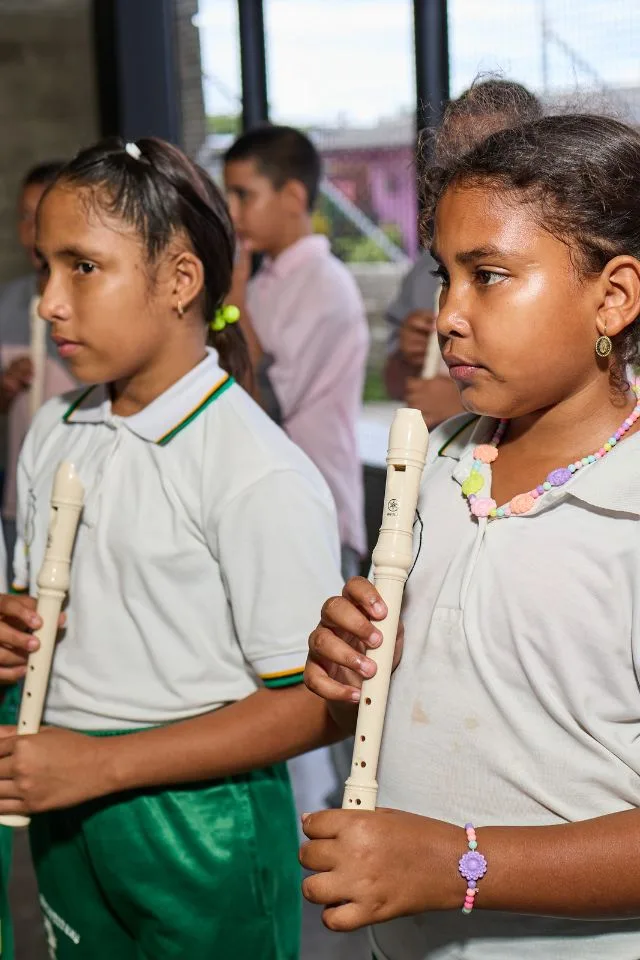 Dos niñas tocan flauta dulce durante una clase de música del programa FilU de la Orquesta Filarmónica de Medellín.