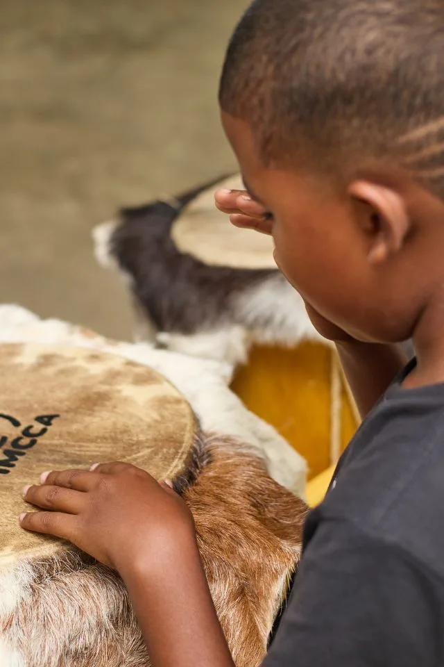 Niño toca un tambor de cuero durante una clase del programa FilU de la Orquesta Filarmónica de Medellín.