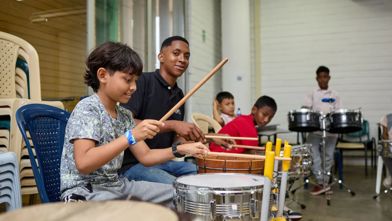 Niño toca tambor junto a su profesor y otros compañeros durante una clase del programa FilU de la Orquesta Filarmónica de Medellín.