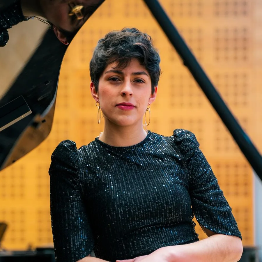 Retrato de María Camila Barbosa, directora asociada de la Orquesta Filarmónica de Medellín, junto a un piano de cola.